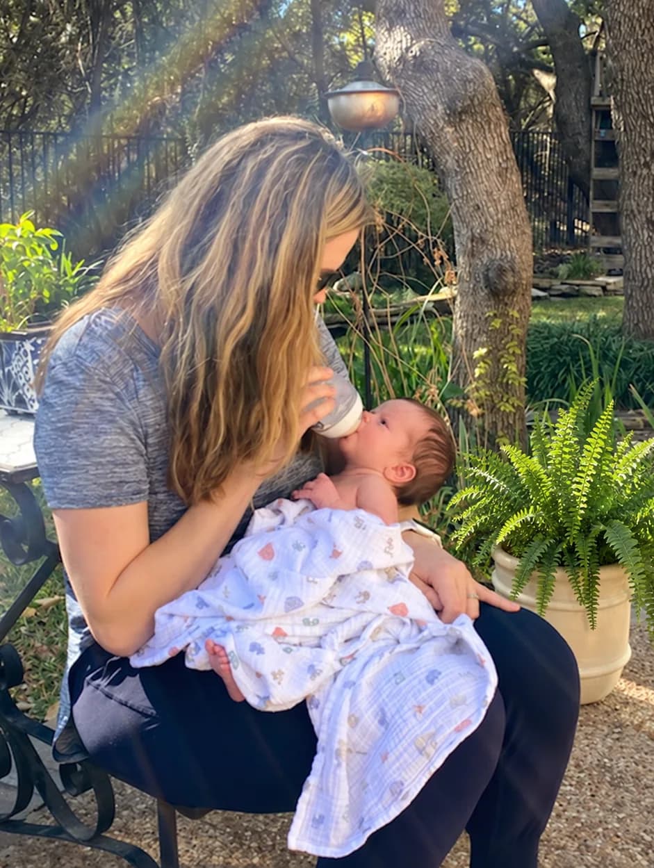 Dr. Jana Rundle feeding her newborn in a backyard chair